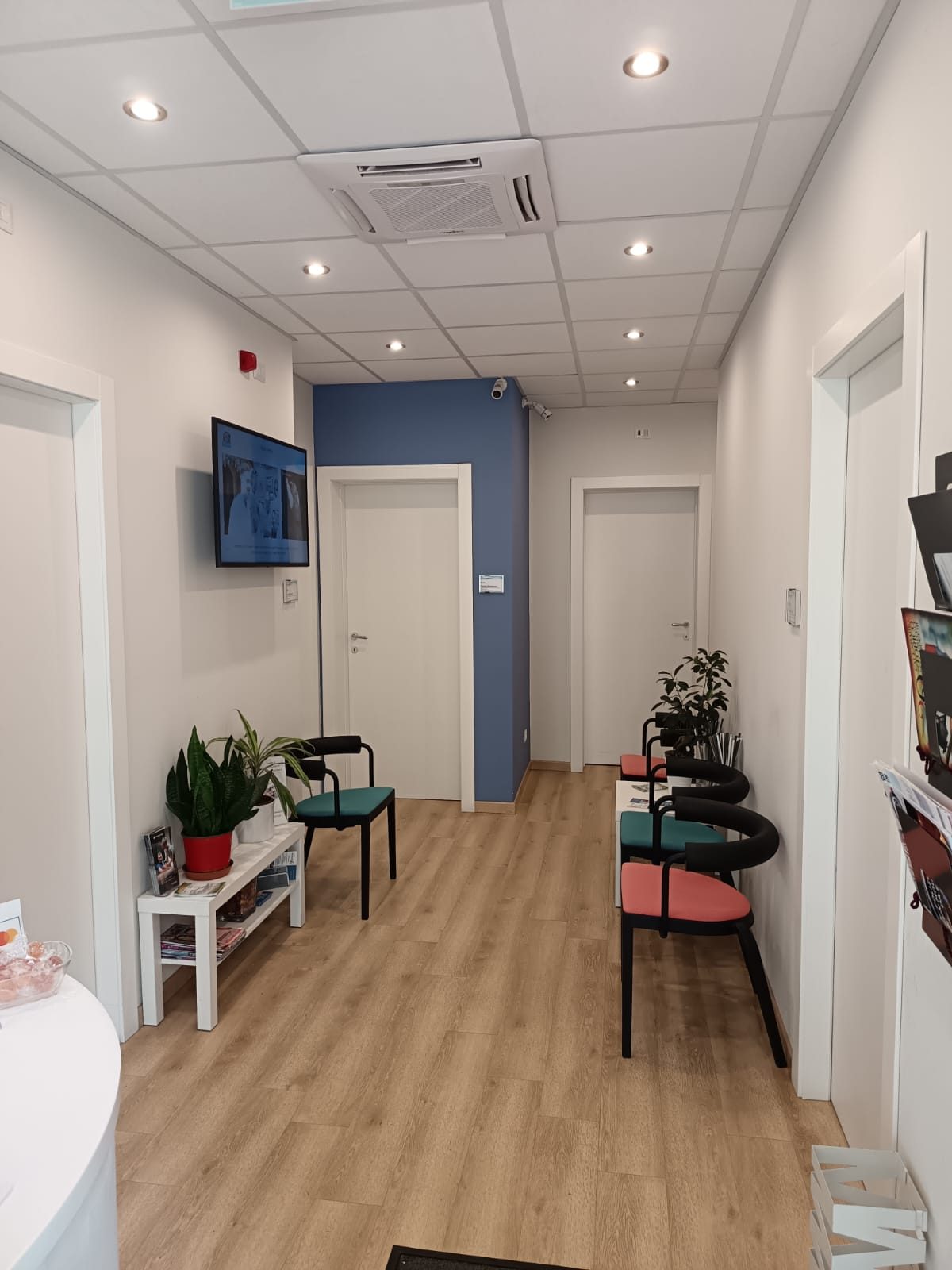 La sala d'attesa del Centro Fisio di Fidenza, con parete blu e ingresso agli ambulatori
